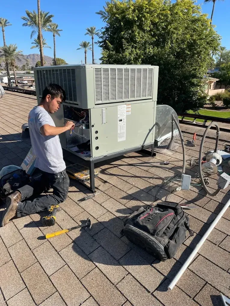 Technician repairing an air conditioning unit on a rooftop.