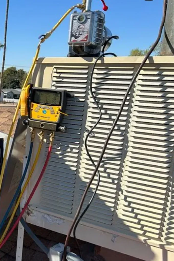 HVAC unit with gauges and hoses connected for maintenance.